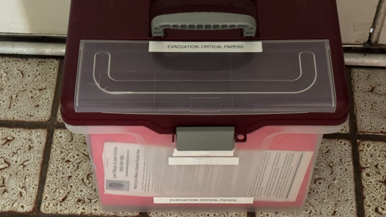 A portable plastic file box labeled "EVACUATION: CRITICAL PAPERS"